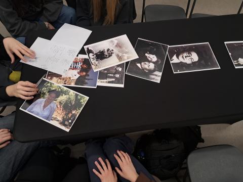 Young people sitting at a table, in front of them there are archival photographs