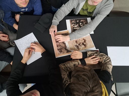 Young people sitting at a table, in front of them there are archival photographs